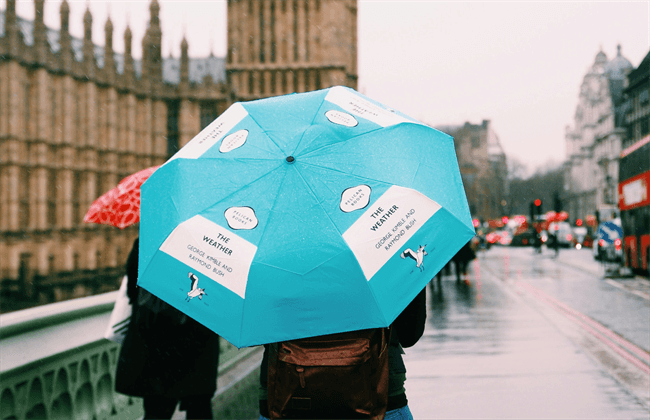 A person holding a blue umbrella on a rainy London street