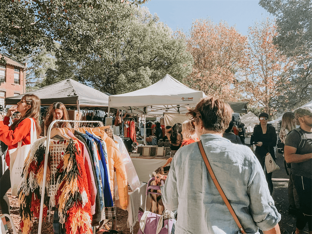 A busy festival booth with clothes for sale.